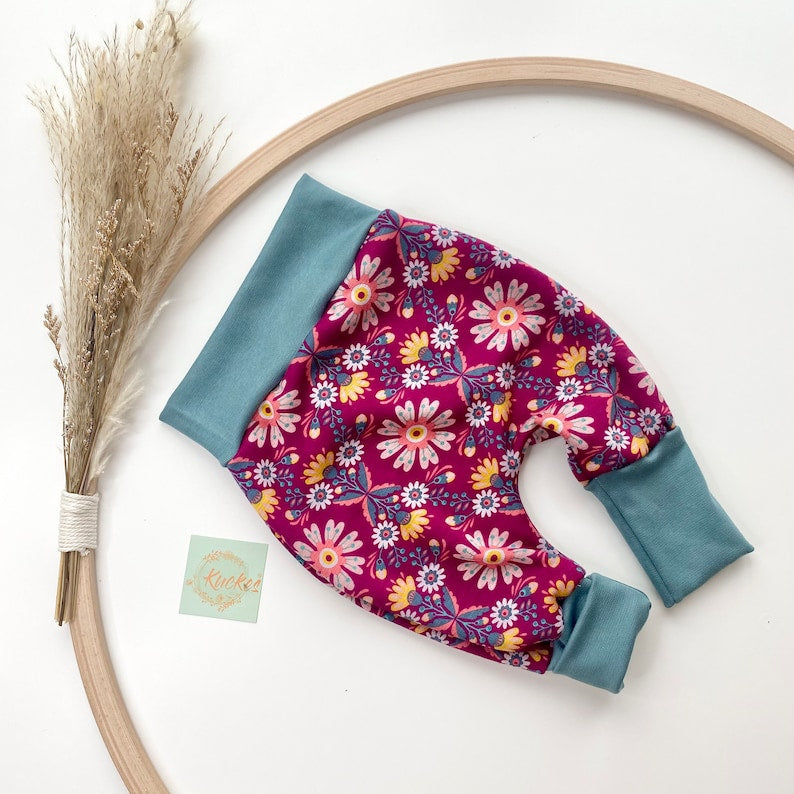Pumphose für Kleinkinder aus Alpenfleece mit weinrotem Stoff und Blumenmuster und türkisen Bündchen.