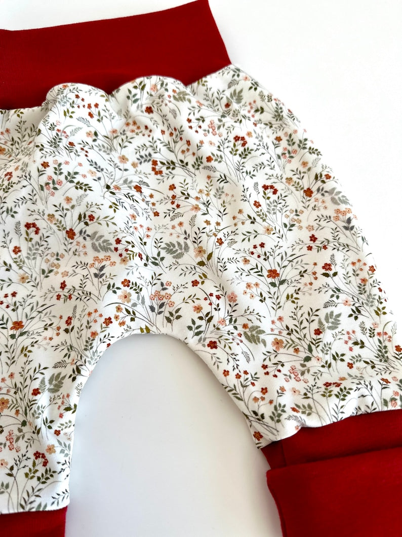 Pumphose für Kleinkinder mit Stoff aus Ribjersey mit weißem Stoff, Wildblumen und roten Bündchen.
