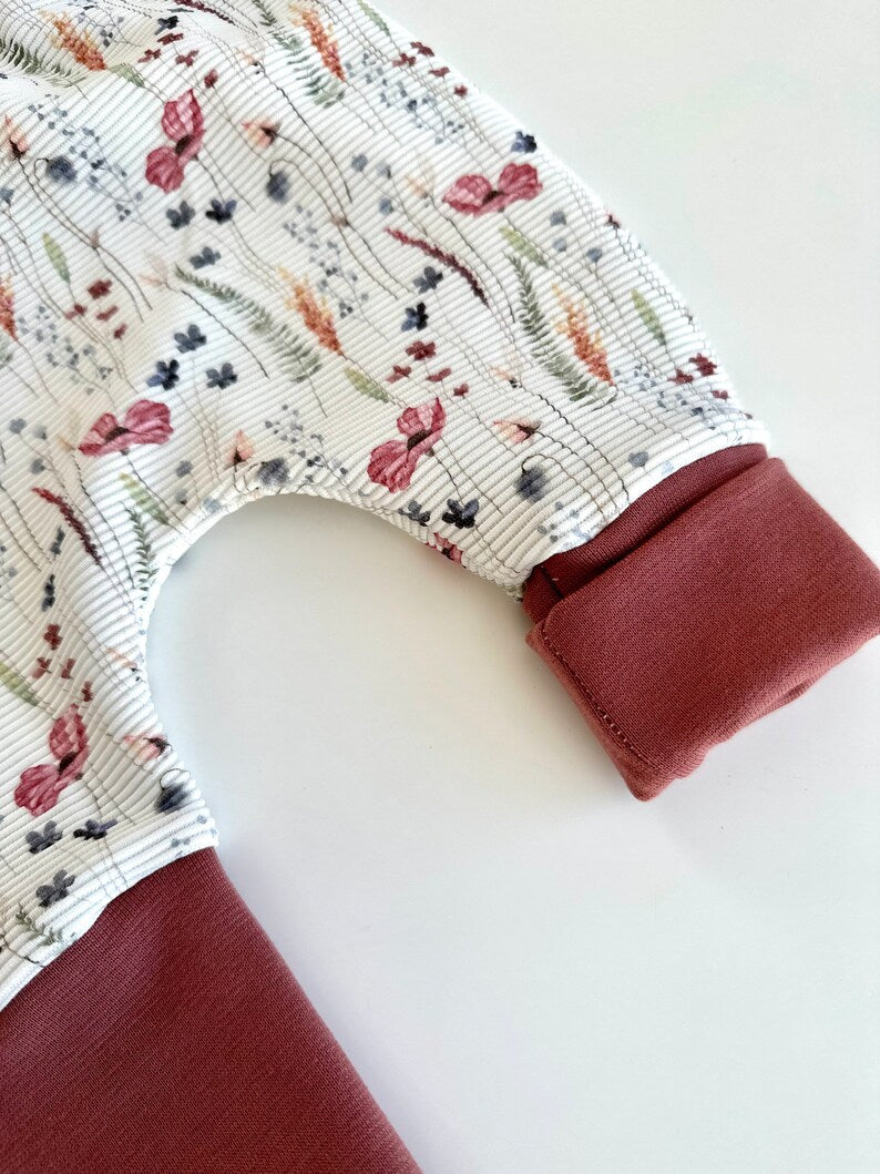 Pumphose für Kleinkinder mit Stoff aus Ribjersey mit Blumenmuster auf weißem Stoff und Dunkelroten Bündchen.