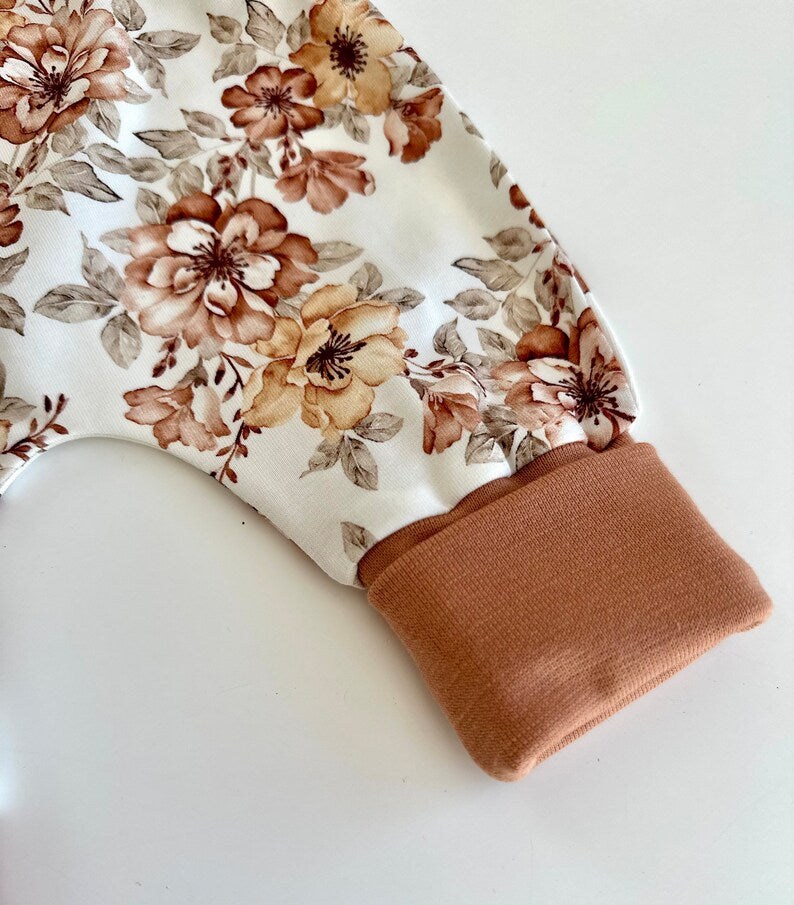 Pumphose für Kleinkinder mit weißem Stoff, braunen Blumen und braunen Bündchen.